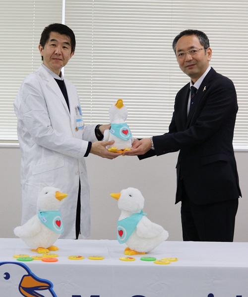 柏支社長(右)からアヒル型ロボットを受け取る岡田教授